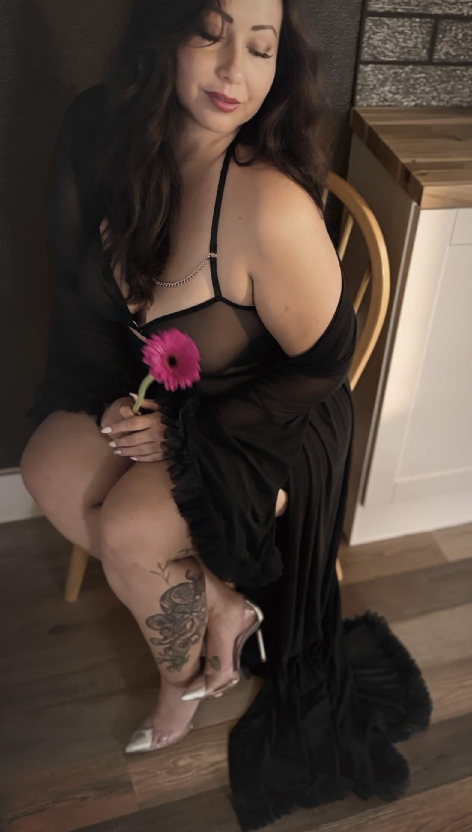 Miss Anna Reigns seated, holding a pink gerbera